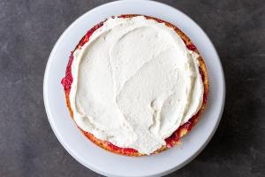 A slice of sponge cake with cranberry sauce and cream.