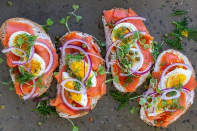 Smoked Salmon toast with toppings and herbs.