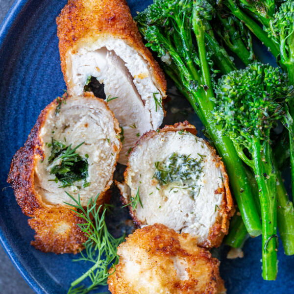 Sliced chicken Kiev on a plate with asparagus.