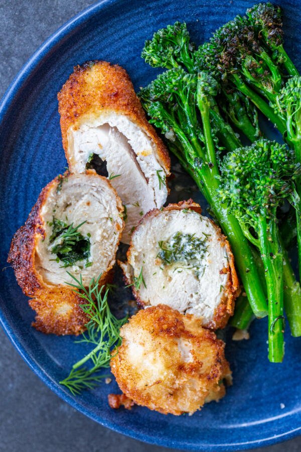 Sliced chicken Kiev on a plate with asparagus.