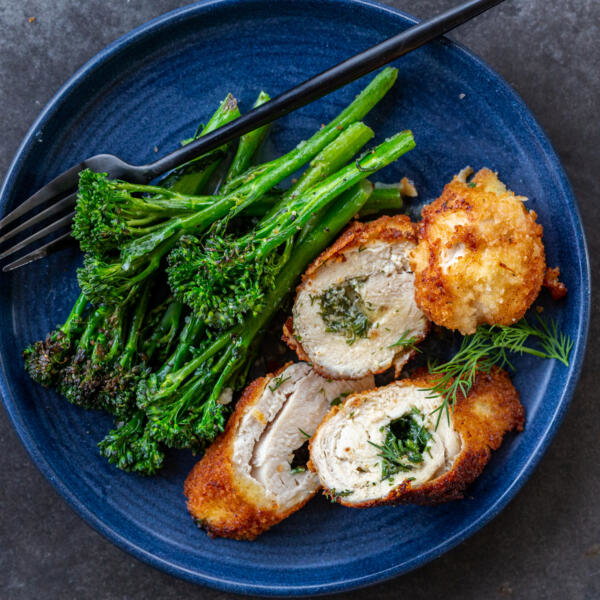 Sliced up chicken Kiev on a plate with cooked asparagus.