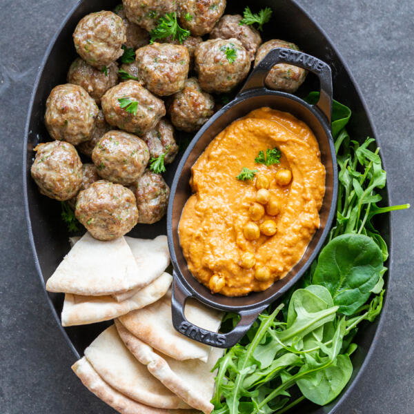 Serving tray with meatballs, hummus and greens.