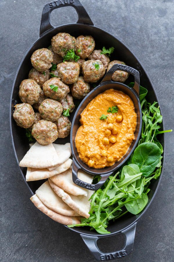 Serving tray with meatballs, hummus and greens.