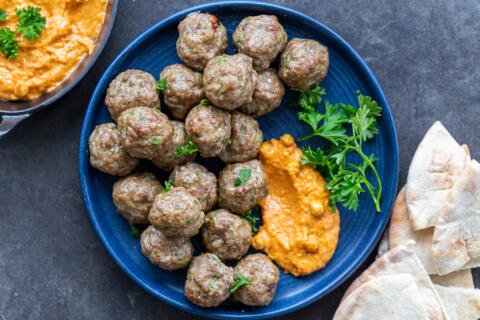Lamb Meatballs on a plate with hummus and herbs.