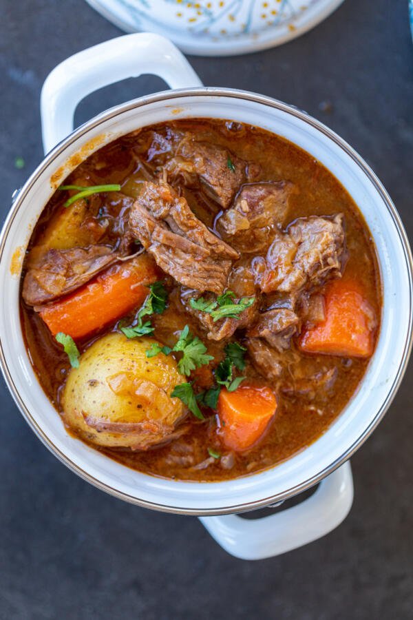 Lamb stew in a pot with potatoes and carrots.