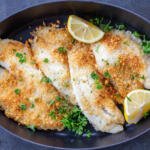 Parmesan Crusted Tilapia on a tray with lemon.
