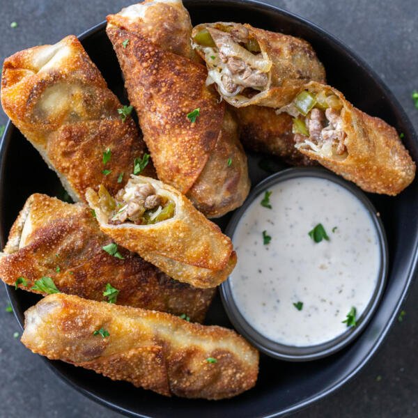 Philly Cheesesteak Egg Rolls on a plate with dipping sauce.
