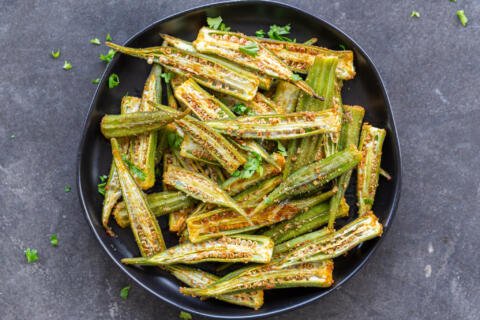 Roasted okra on a plate with herbs.