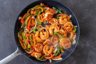 Shrimp with veggies cooking in a pan.