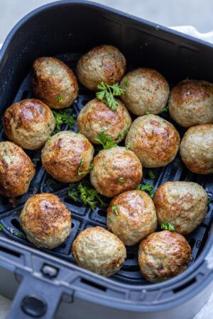 Turkey meatballs in an air fryer basket.