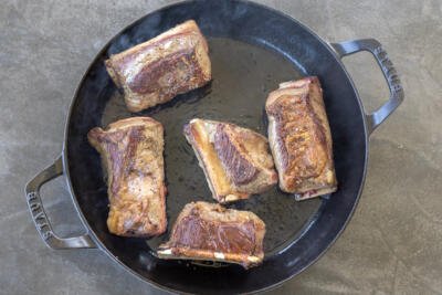 Browned beef short ribs in a pan.