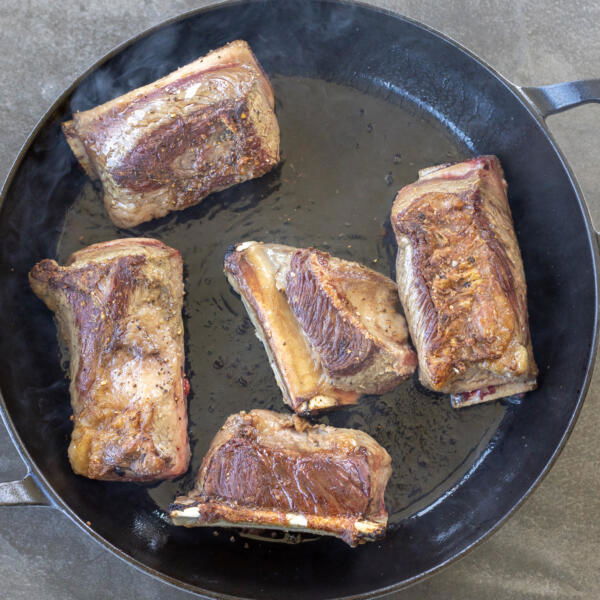 Browned beef short ribs in a pan.