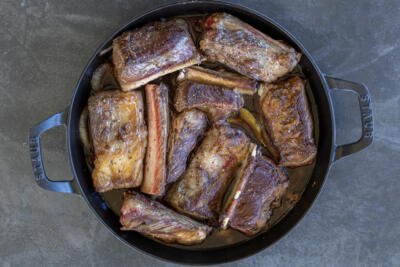 Braised short ribs in a pan with sauce.