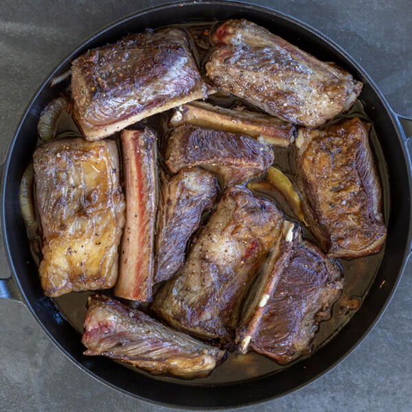 Braised short ribs in a pan with sauce.