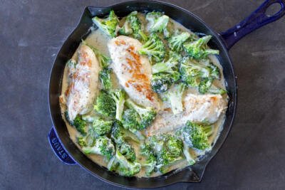 Chicken and broccoli in a pan with creamy sauce.