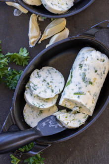 Sliced up butter in a pan with a knife.
