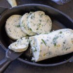 Herb butter sliced into pieces in a pan.