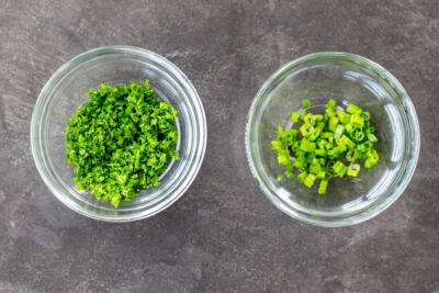 Parsley and onion diced in two bowls.