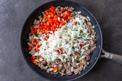 Breakfast sausage with veggies in a pan.