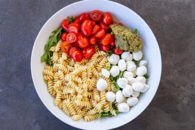 Pasta salad ingredients lined up in a bowl.