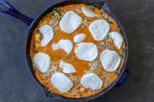 Cheese on top of gnocchi in a pan.