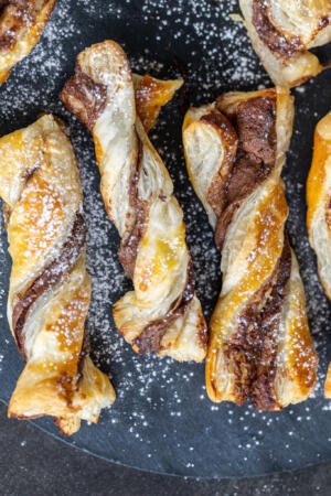 Puff Pastry Nutella Twists on a tray with powdered sugar.