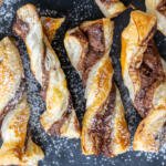 Baked puff pastry with nutella on a tray with powdered sugar.