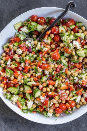 Mediterranean Chickpea Salad in a bowl with a serving spoon.