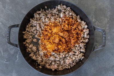 Taco seasoning added to the ground beef in a pan.