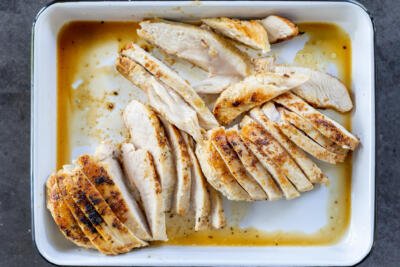 Sliced up chicken thats cooked, on a tray.