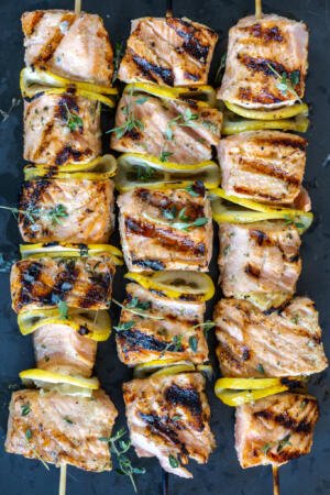 Grilled Salmon Kebabs on a tray with herbs.