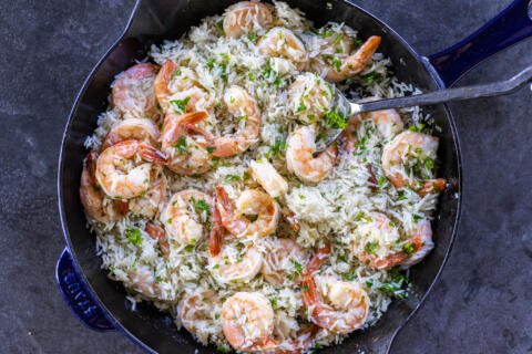 Shrimp & Rice in a pan with parsley and a serving spoon.