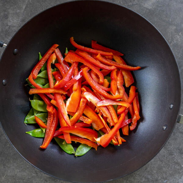 Bell peppers and snow peas in a pan.