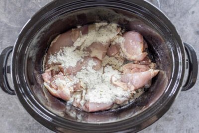 Chicken with seasoning in a slow cooker.