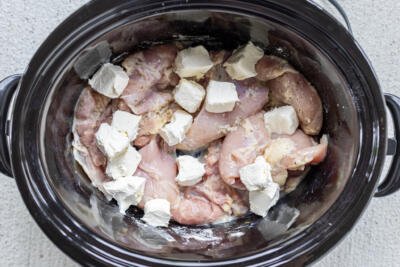Cream cheese added to the slow cooker and chicken.