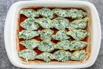 Stuffed shells on a baking pan with sauce.