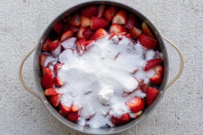 Sugar added to the strawberries in a pot.