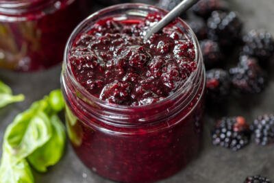 Jar with Blackberry Jam with fresh berries next to it.