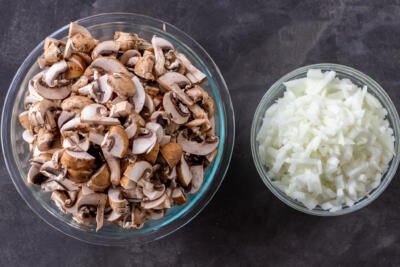 Diced mushrooms and onions in two bowls.