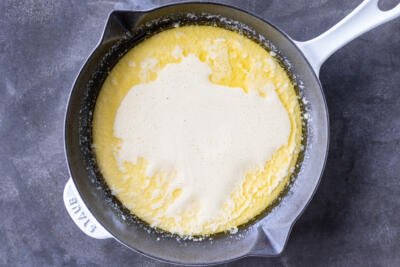 German Pancakes batter inside the pan with melted butter.
