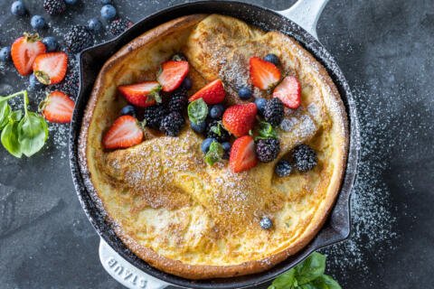 German Pancake in a pan with powdered sugar with berries.