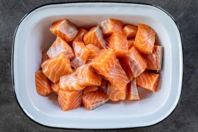 Sliced salmon into bite size pieces in a bowl.