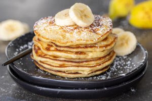 A stack of Banana Pancakes with slices of bananas on top.