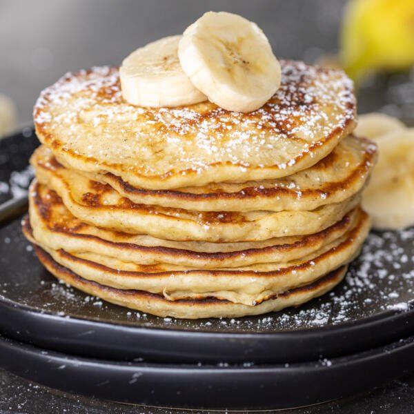 A stack of Banana Pancakes with slices of bananas on top.