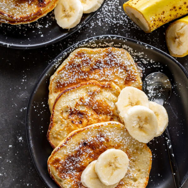 Banana Pancakes on a plate with slices of banana.