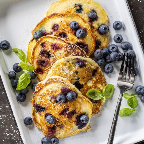 A plate with pancakes and berries with herbs.