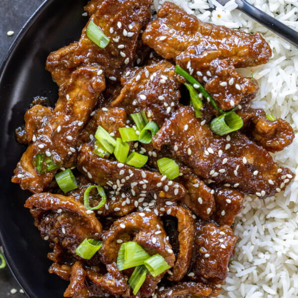 A plate with Mongolian Beef, rice and green onions.