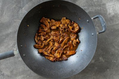 A wok with beef and sauce.