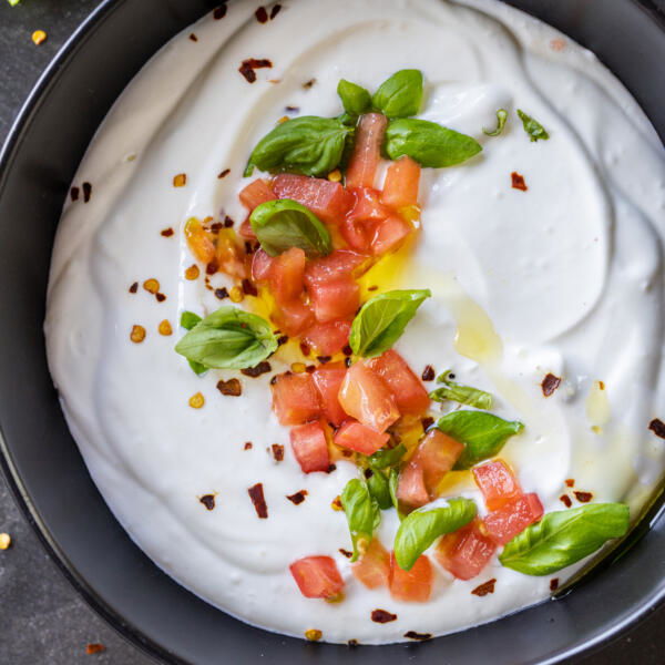 A bowl with creamy cottage cheese with herbs and tomatoes.