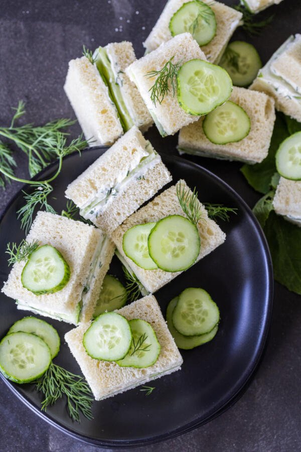 Mini Cucumber Sandwiches on a plate with herbs.